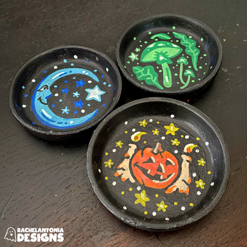 3 Black dishes with a green mushroom, a jack o lantern, and a blue moon on them