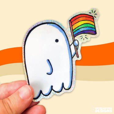 photo of rachels hand holding a sparkly sticker that features a ghost holding a rainbow pride flag